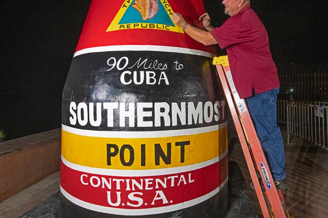 <p>In this photo provided by the Florida Keys News Bureau, Key West Public Works employee Paul Cassidy puts finishing touches on the Southernmost Point marker Thursday, Jan. 6, 2022, in Key West, Fla. </p>