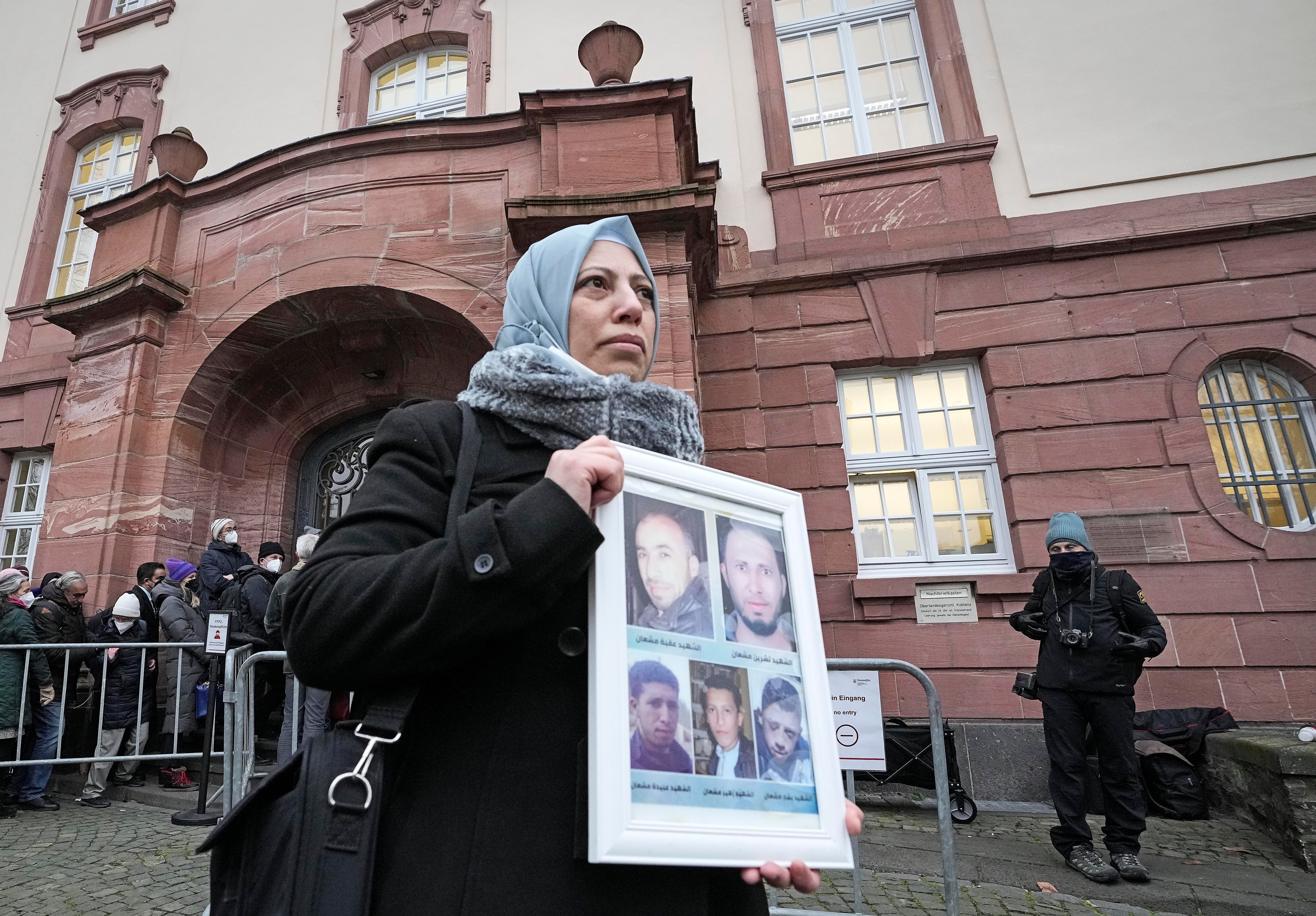 Syrian woman Yasmen Almashan holds the pictures of her five brothers, who died in Syria, before the verdict in front of the court in Koblenz, Germany