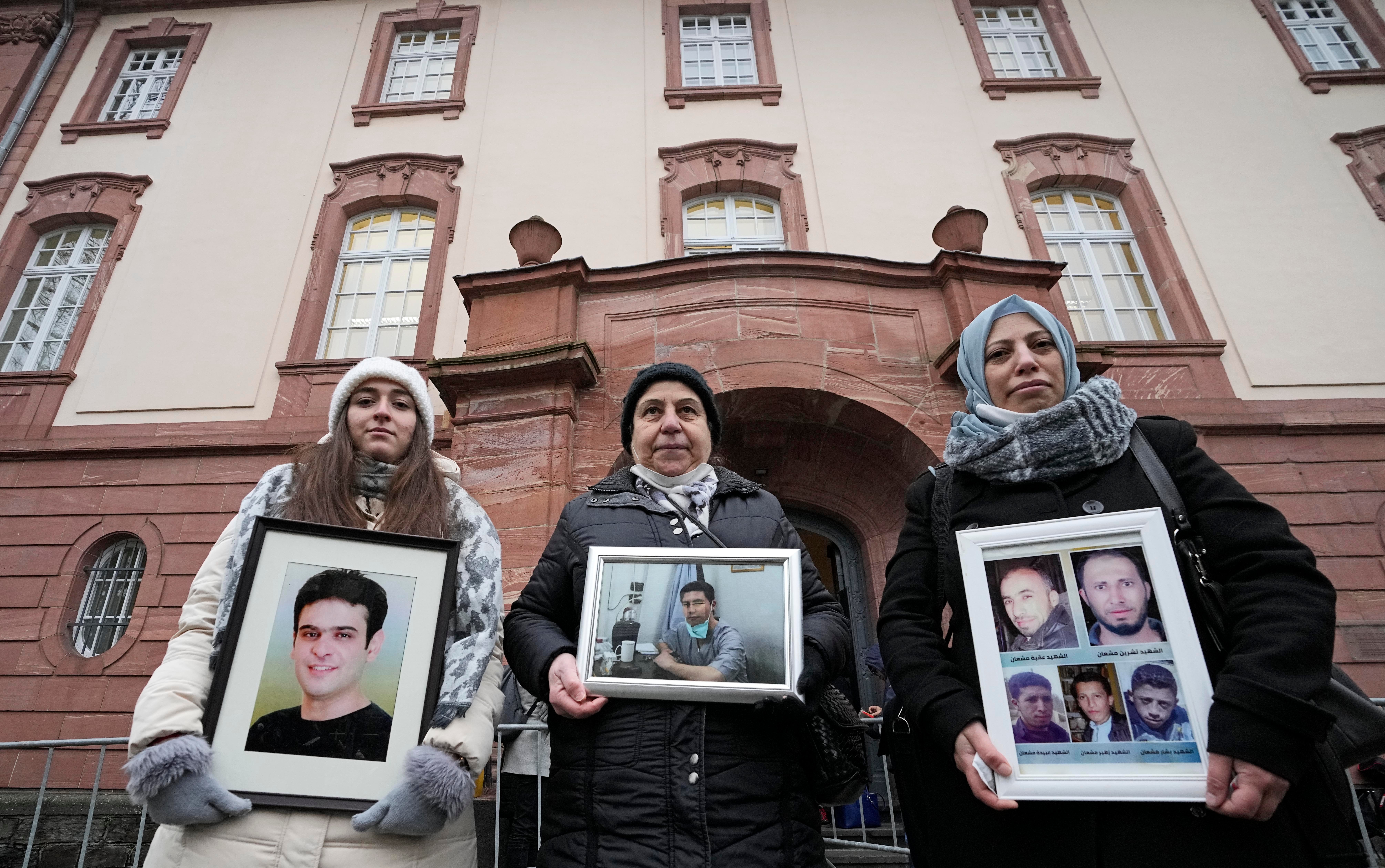 Syrian women Samaa Mahmoud, Mariam Alhallak and Yasmen Almashan hold pictures of relatives who died in Syria, before the verdict in front of the court in Koblenz, Germany