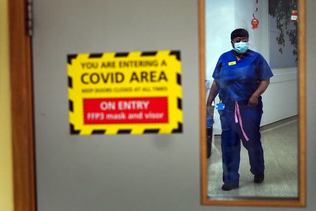 <p>A nurse walks through a Covid ward</p>