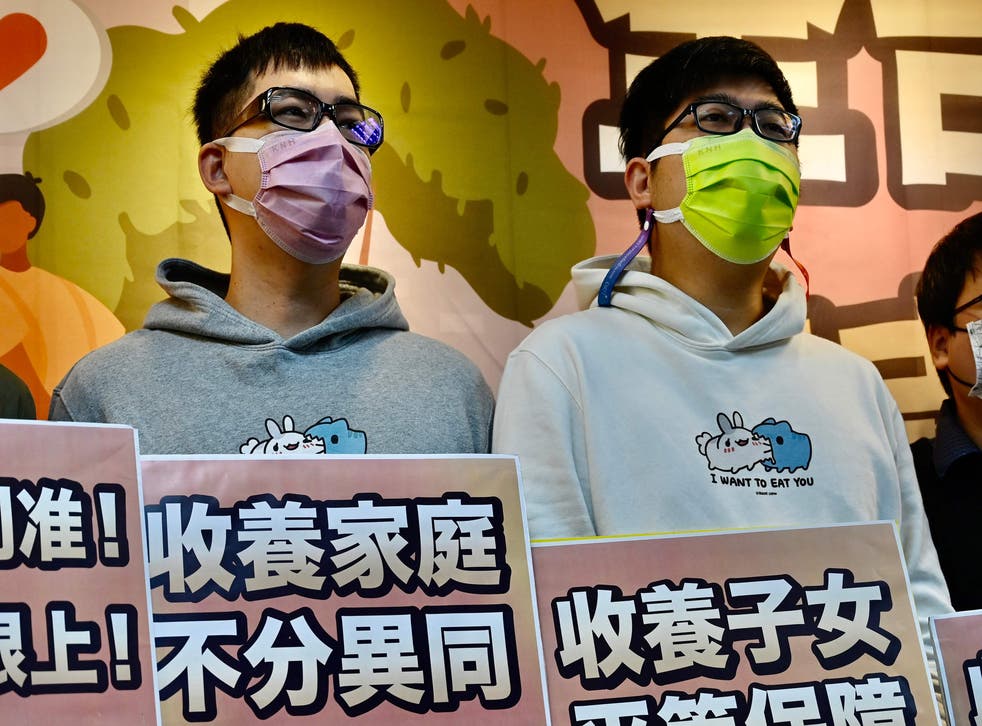 <p>Taiwanese couple Chen Jun-ru (L) and Wang Chen-wei display signs seeking fair laws for adoption on 13 January, 2022 </p>