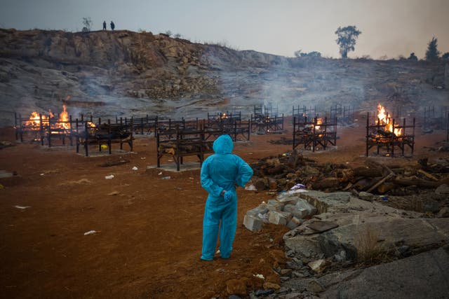 Archivo: Un hombre con PPE (Equipo de Protección Personal) observa cremaciones masivas durante la segunda ola de la pandemia de coronavirus el 30 de abril de 2021 en Bangalore, India