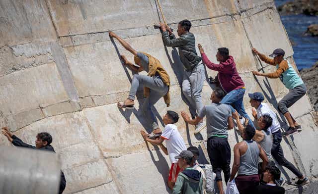 <p>Migrants climb a sea wall in the northern Morocco town of Fnideq after attempting to cross the border to Spain’s north African enclave of Ceuta last May </p>
