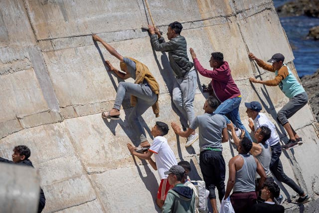 <p>Migrants climb a sea wall in the northern Morocco town of Fnideq after attempting to cross the border to Spain’s north African enclave of Ceuta last May </p>