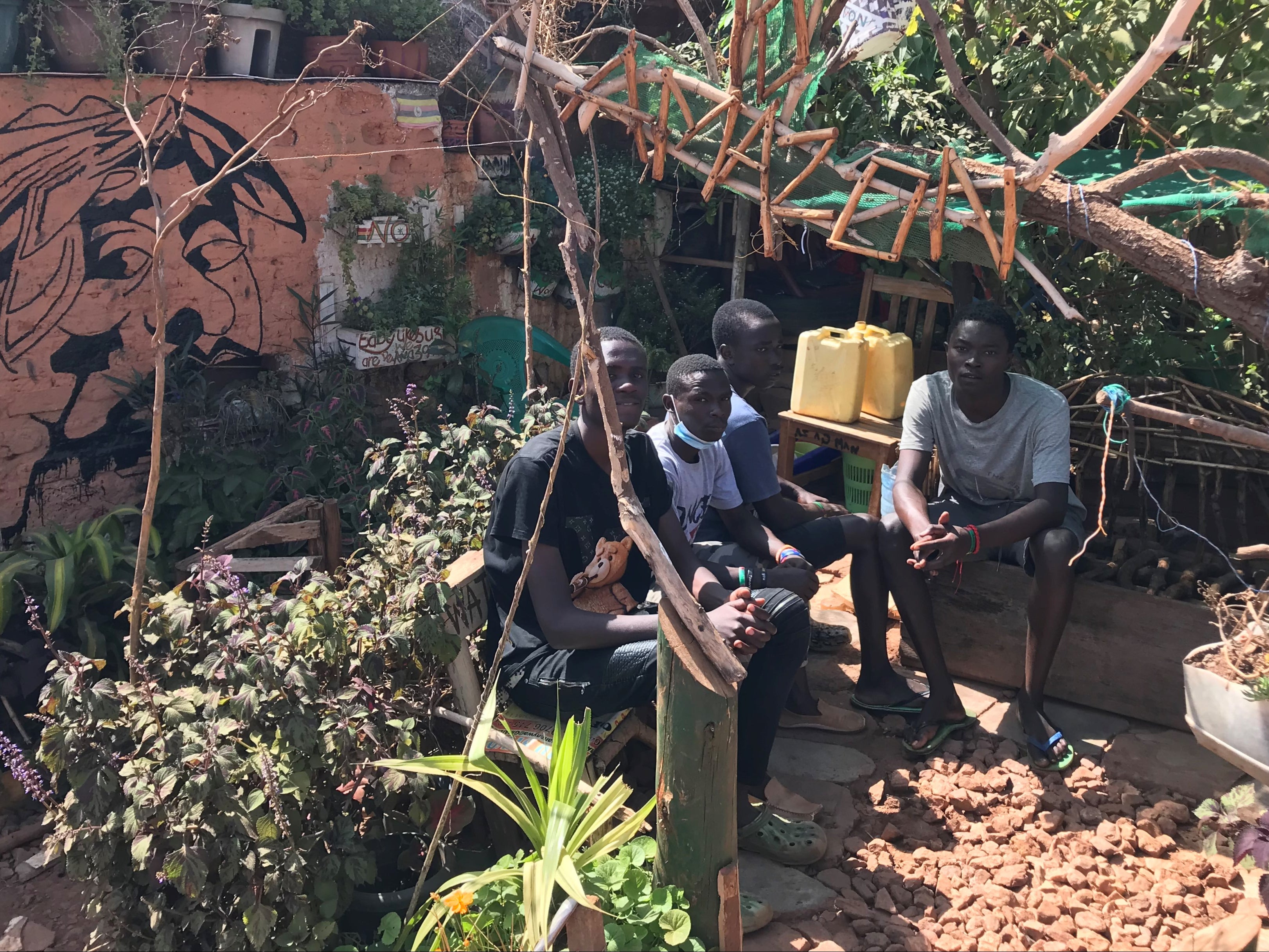 Muhammed Asiimwe (second left) sits in ‘Amazon’, a hangout spot he and his friends built in the Naguru Go Down slum during Uganda’s school shutdown