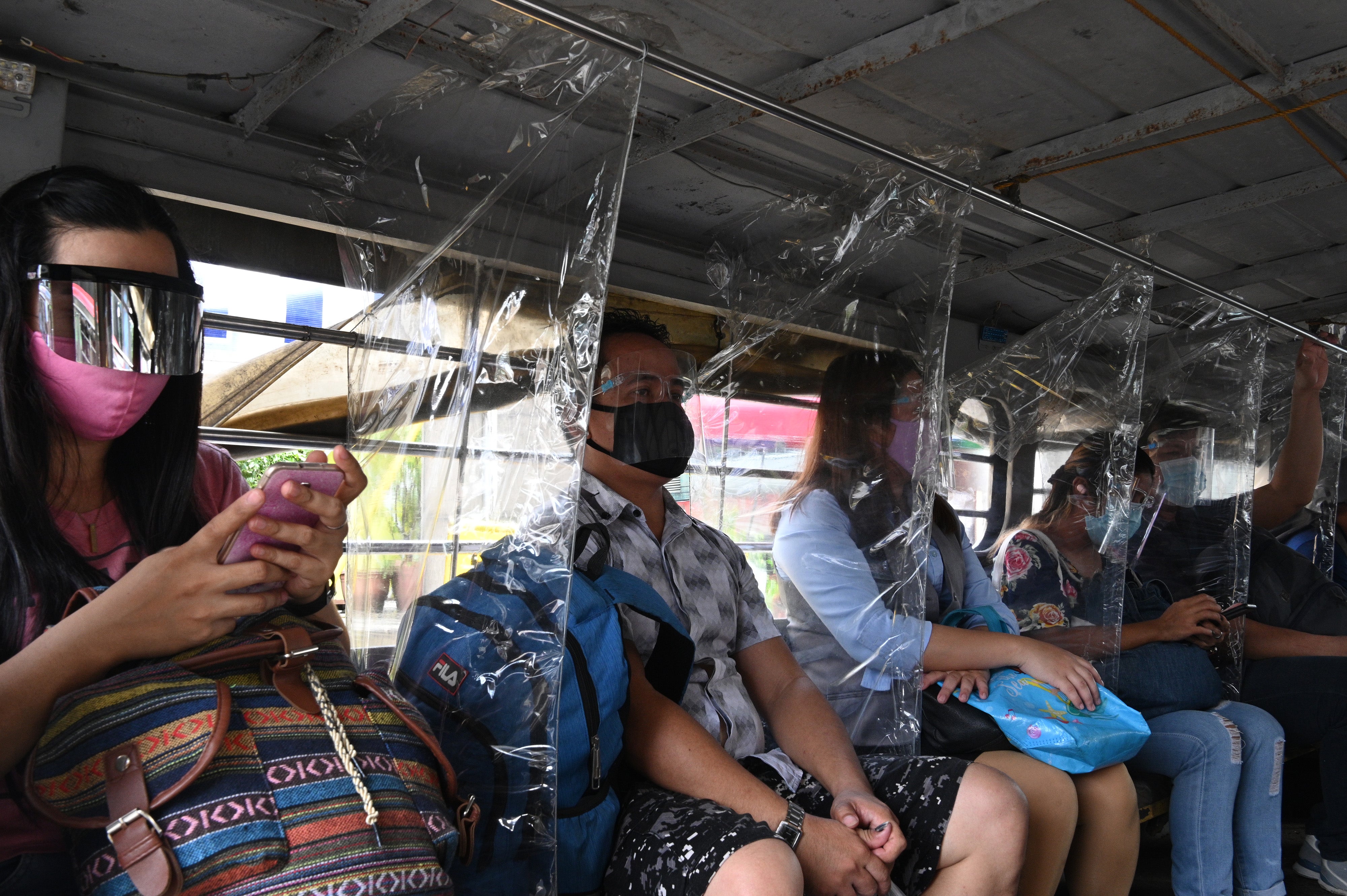 Passengers wearing face shields sit next to plastic dividers on public transport in Manila, Philippines, last year