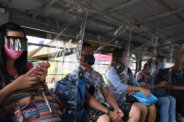 <p>Passengers wearing face shields sit next to plastic dividers on public transport in Manila, Philippines, last year </p>
