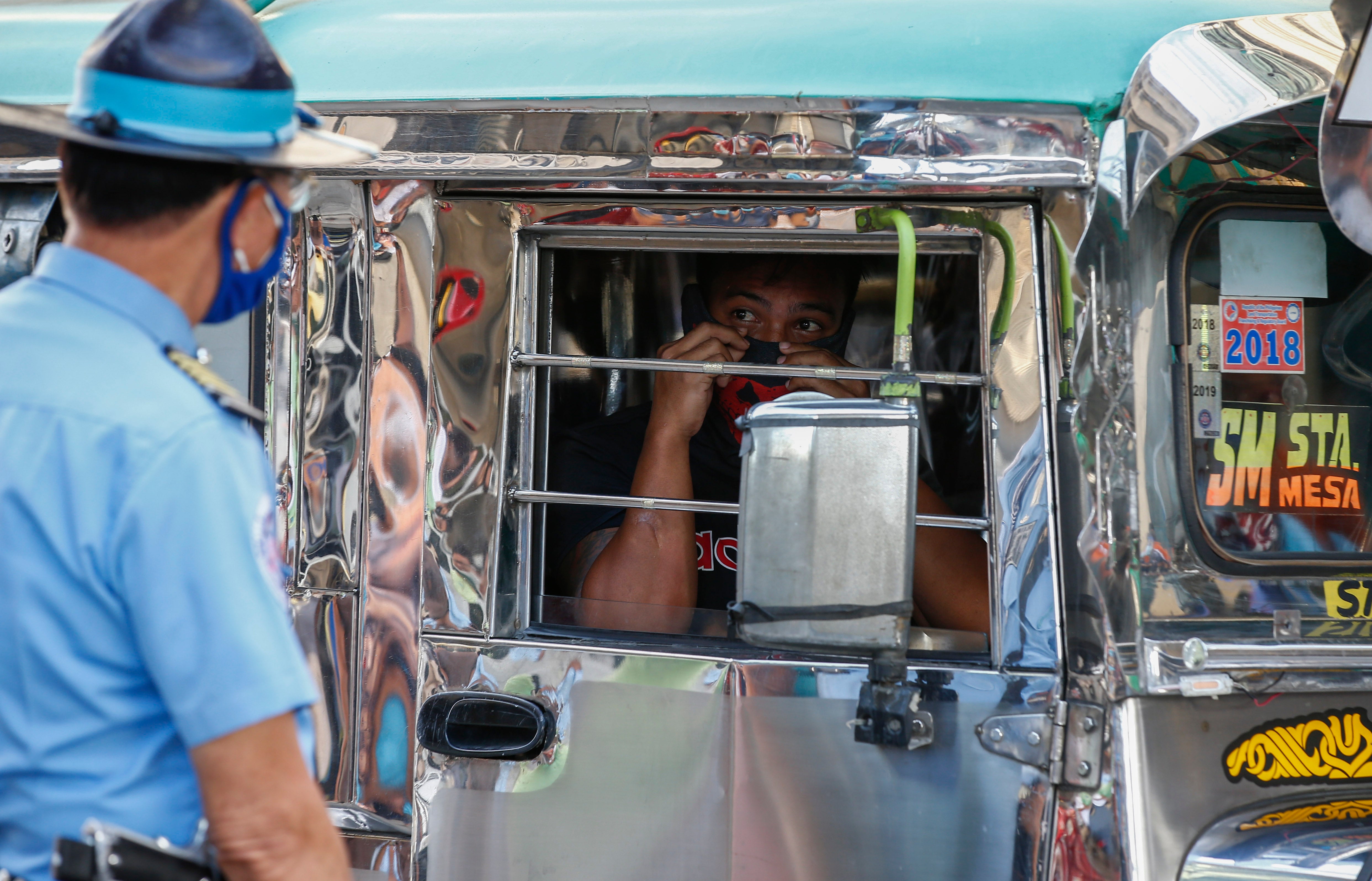 A passenger of a minibus, locally known as jeepney, speaks to a transport official in Quezon City, Manila, 3 July 2020