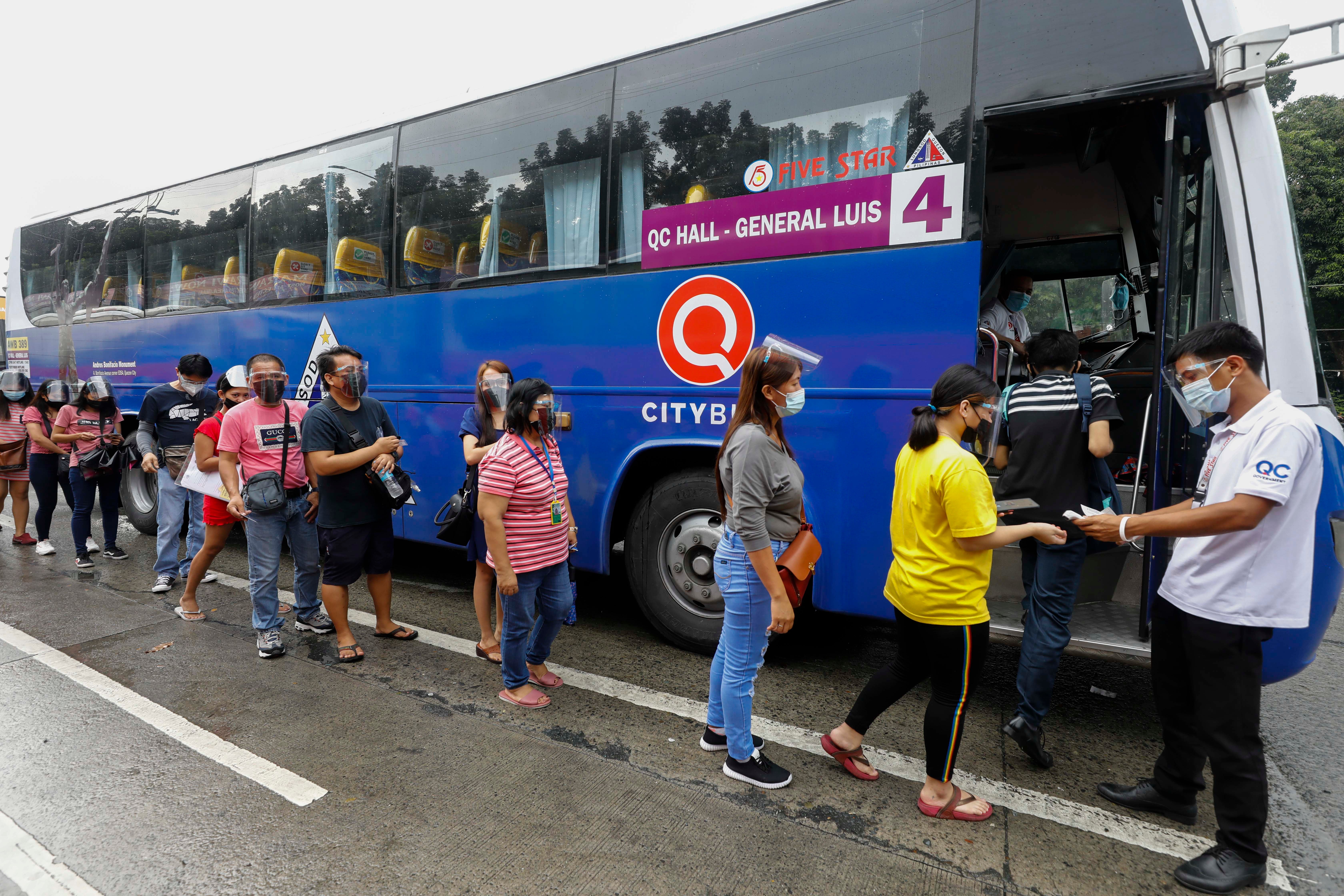 Passengers queue to board a bus in Quezon City, Manila, 24 August 2021