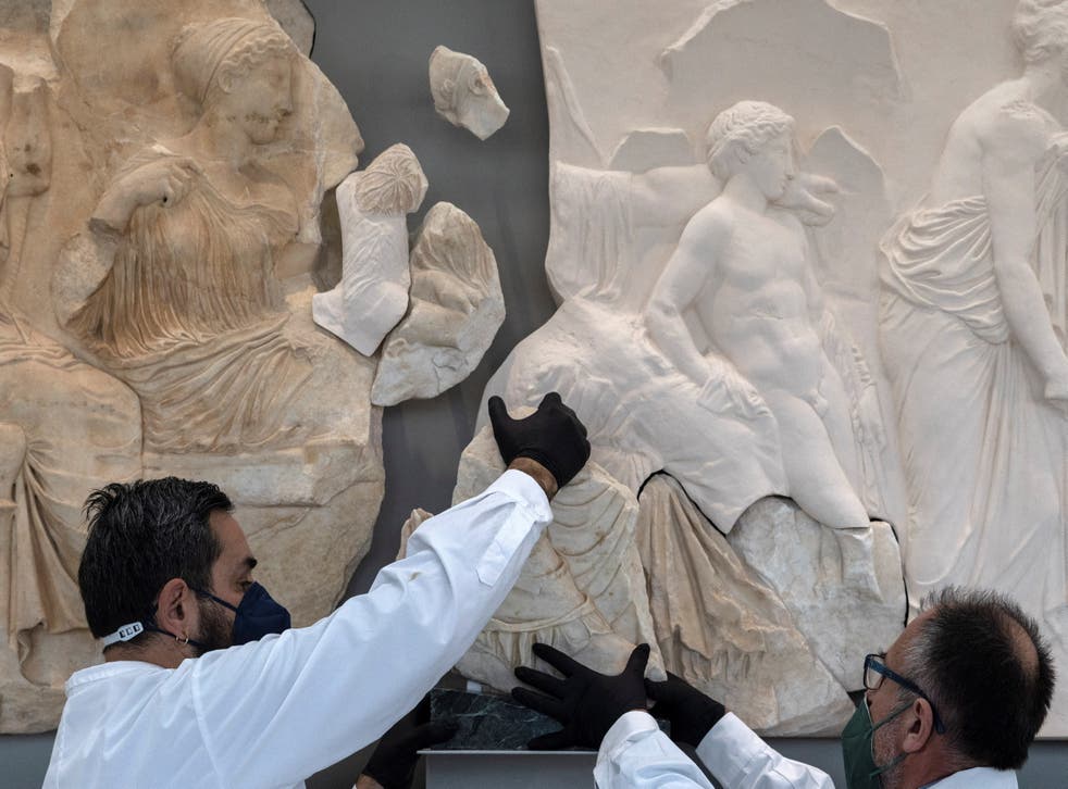 <p>Two conservators hold a Parthenon fragment, on loan from the Antonino Salinas Regional Archaeological Museum of Palermo, in the Parthenon Gallery at the Acropolis Museum in Athens</p>