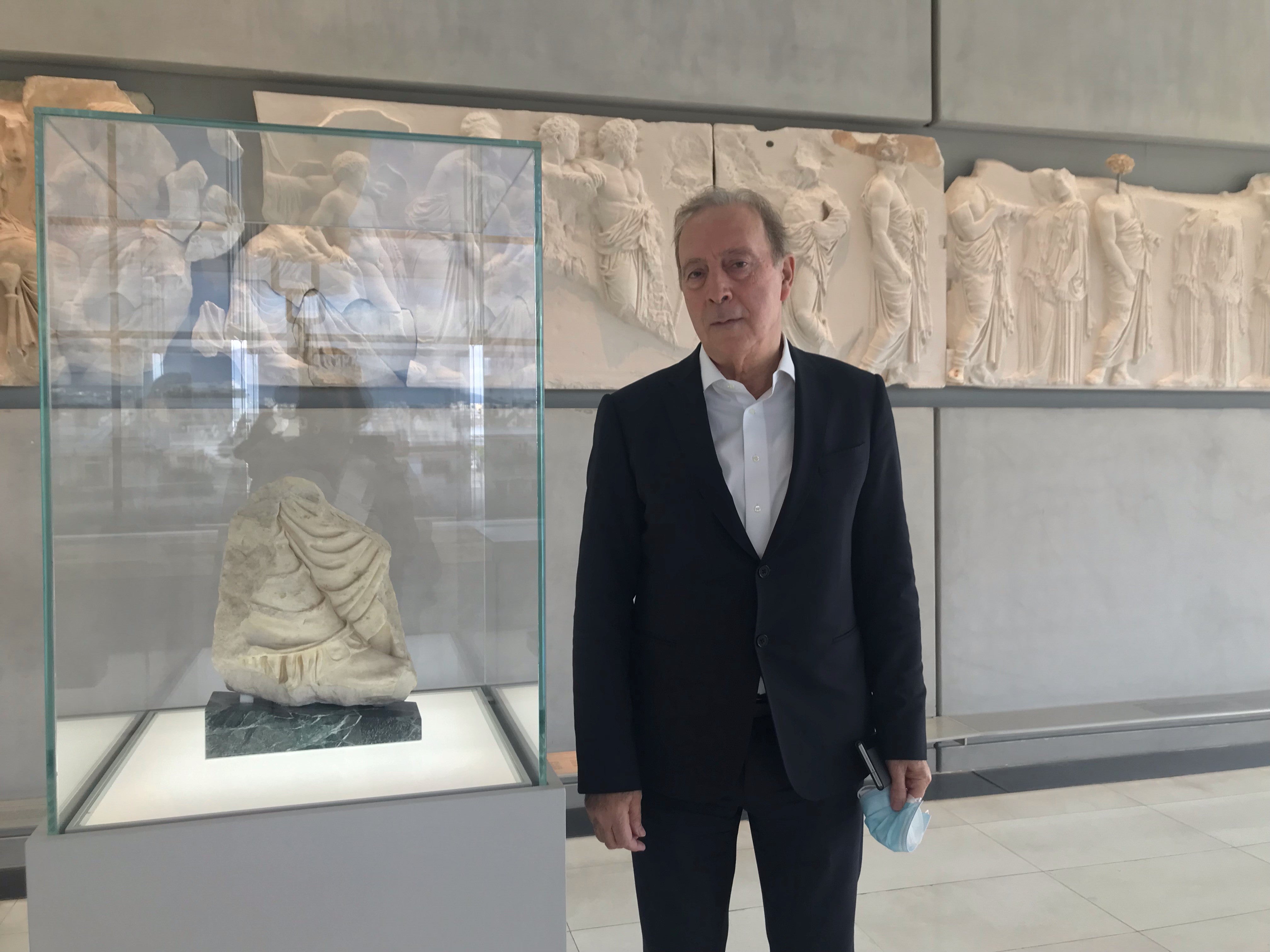 The General Director of the Acropolis Museum, Nikos Stampolidis, stands beside a fragment of the Parthenon frieze newly situated in the Acropolis Museum, Athens