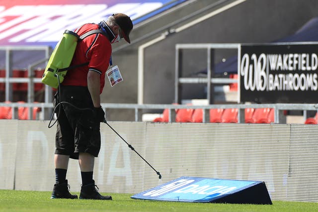A ground staff member disinfects the area around the pitch before the Betfred Super League match at The Totally Wicked Stadium, St Helens.