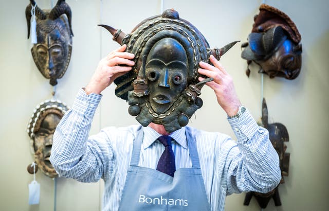 Bonhams’ Danny McIlwraith holds a Nigerian polycrome carved wood mask during a photocall for the sale of the Jim Lennon Collection at Bonhams in Edinburgh