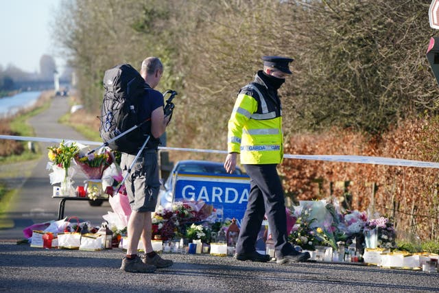 A Garda talks to a rambler by the floral tributes laid at the Grand Canal in Tullamore, Co Offaly (Niall Carson/PA)