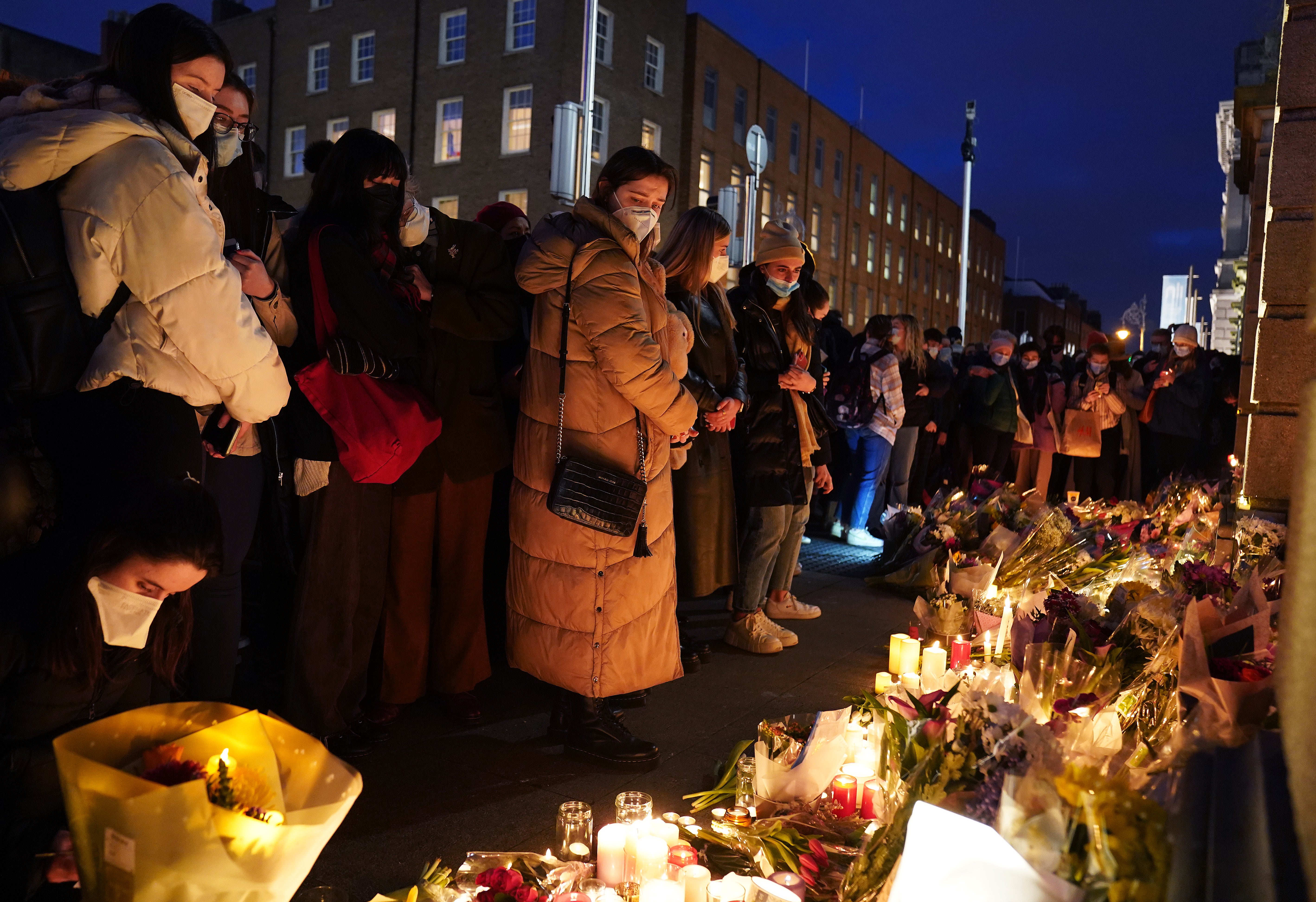 People leave candles and flowers at a make-shift shrine during a vigil at Leinster House, Dublin, for the murdered Ashling Murphy who died after being attacked while she was jogging along the Grand Canal in Tullamore, County Offaly, on Wednesday (Brian Lawless/PA)