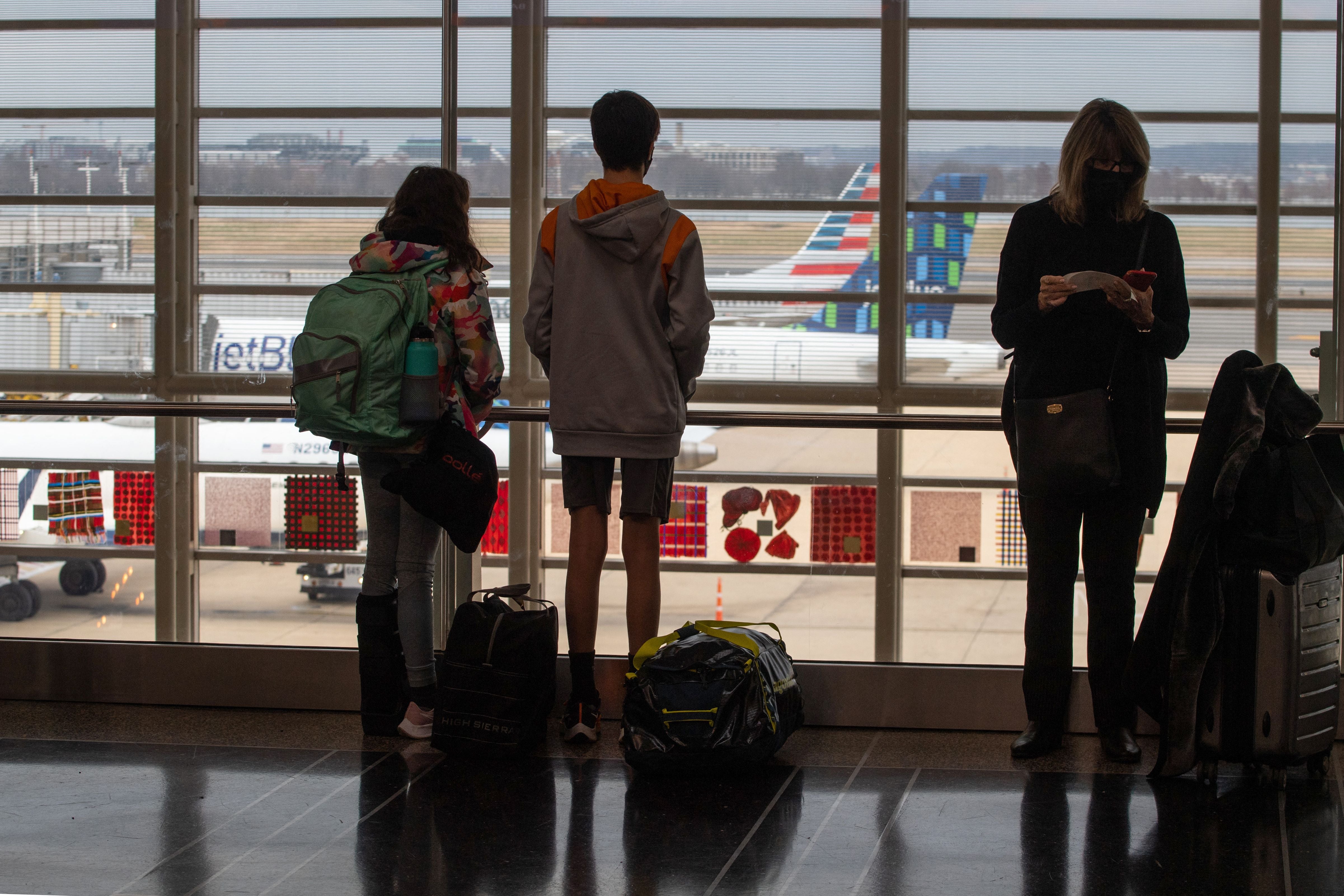 File: Travelers watch planes on the tarmac near checking in counters at Ronald Reagan International Airport in Washington, DC on 27 December 2021