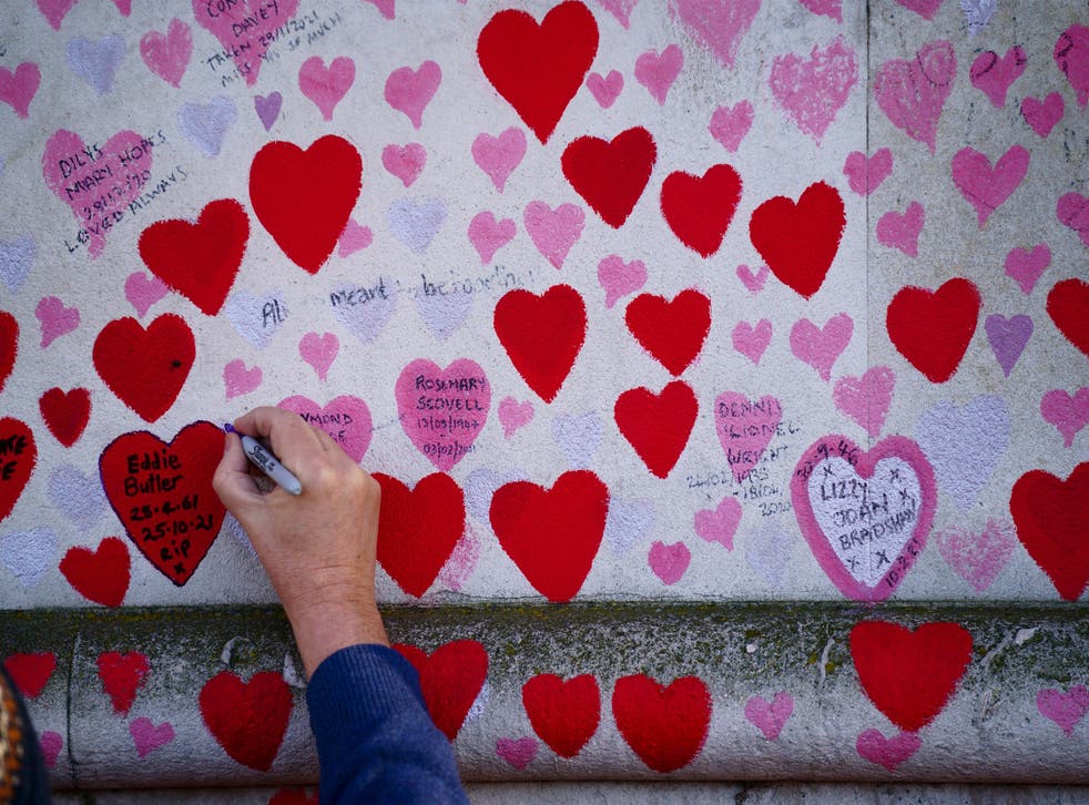 A man writes on a heart at the National Covid Memorial Wall, in Westminster, London. (Victoria Jones/PA)
