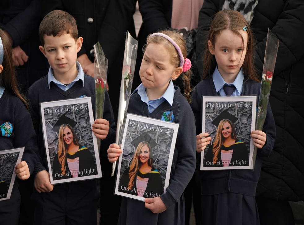 Pupils from Ashling Murphy’s class hold photographs of her (Niall Carson/PA)