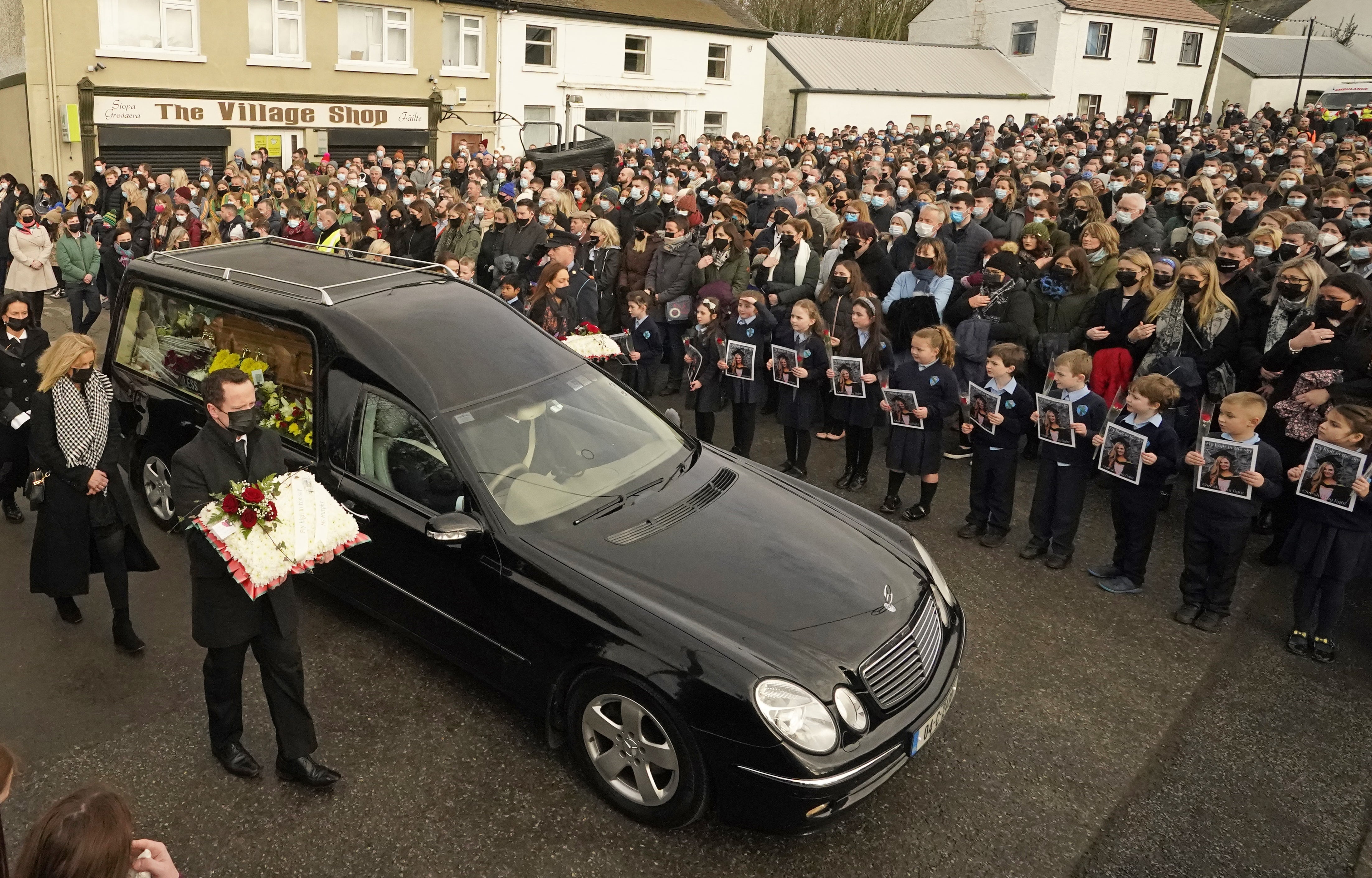 Schoolchildren taught by Ashling Murphy hold photographs of her as the cortege passes by on arrival at St Brigid’s Church, Mountbolus, Co Offaly, for the funeral of Ashling who was murdered in Tullamore, Co Offaly (Niall Carson/PA)