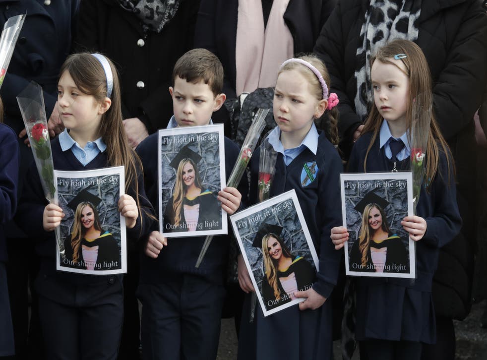 Pupils from Ashling Murphy’s class hold photographs of her and red roses outside St Brigid’s Church, Mountbolus, Co Offaly, for her funeral (PA)