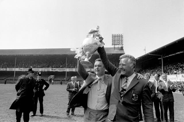 Derby County manager Brian Clough (l) and his assistant Peter Taylor (r) show off the League Championship trophy to the jubilant Derby fans who had packed the Baseball Ground especially to see the trophy (Archive/PA)