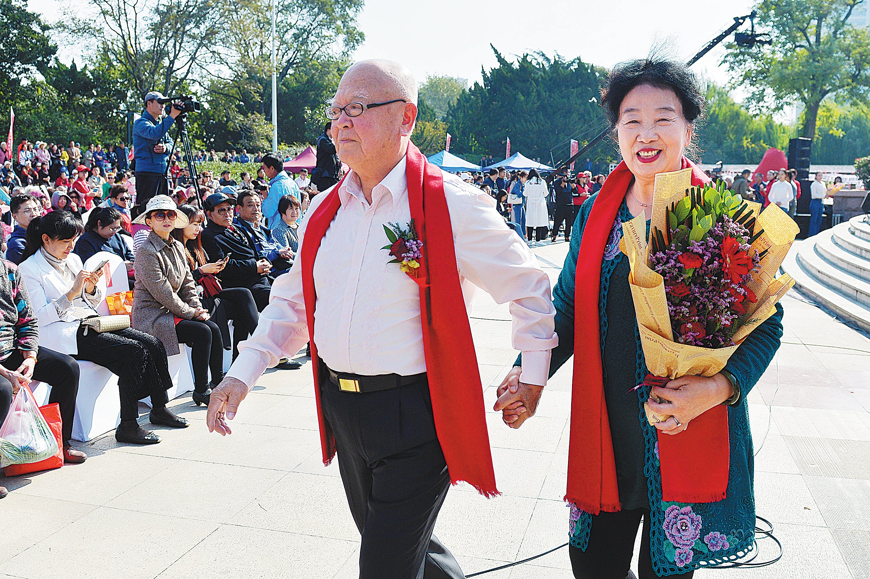 A newly married couple walk hand in hand in a group wedding in Qingdao, Shandong province