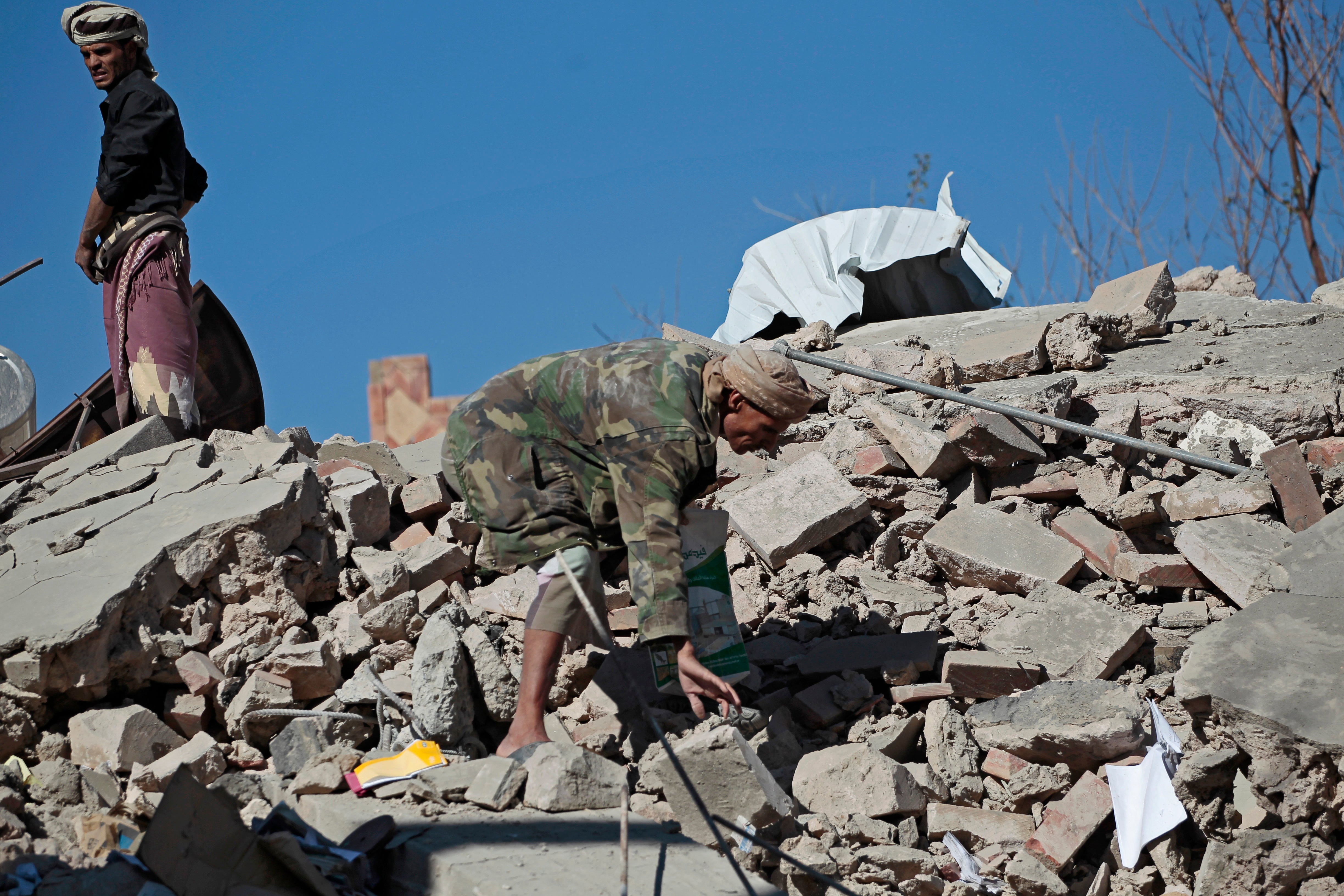 People inspect the wreckage of buildings that were damaged by coalition airstrikes in Saada