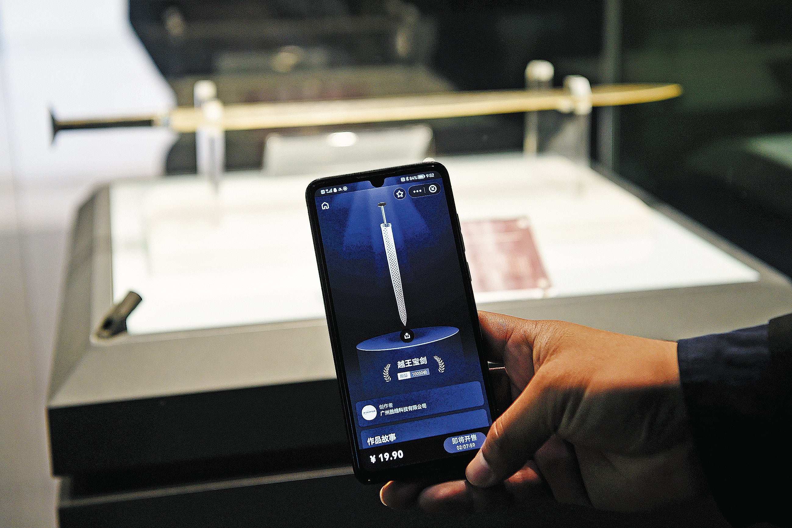 A visitor compares the digital version of the Sword of Gou Jian on his mobile phone with the original on display at the Hubei Provincial Museum in Wuhan, Hubei province