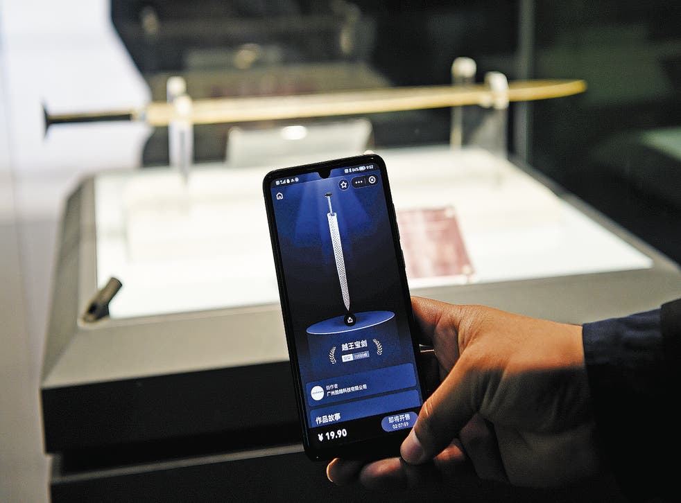 <p>A visitor compares the digital version of the Sword of Gou Jian on his mobile phone with the original on display at the Hubei Provincial Museum in Wuhan, Hubei province</p>