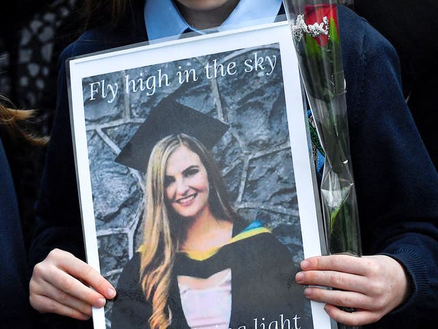 <p>A pupil from Ashling Murphy’s class holds a photograph of her and a red rose ahead of her funeral in County Offaly</p>
