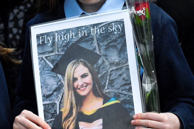 <p>A pupil from Ashling Murphy’s class holds a photograph of her and a red rose ahead of her funeral in County Offaly</p>