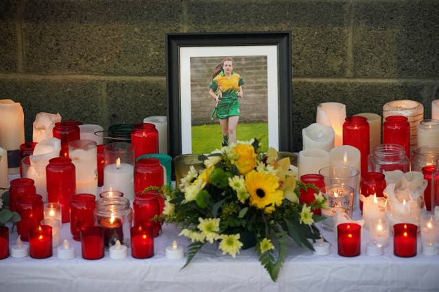 Floral tributes and candles surround a photograph at Kilcormac Killoughey GAA Club, for Ashling Murphy who was found dead after going for a run in Co Offaly (Niall Carson/PA)