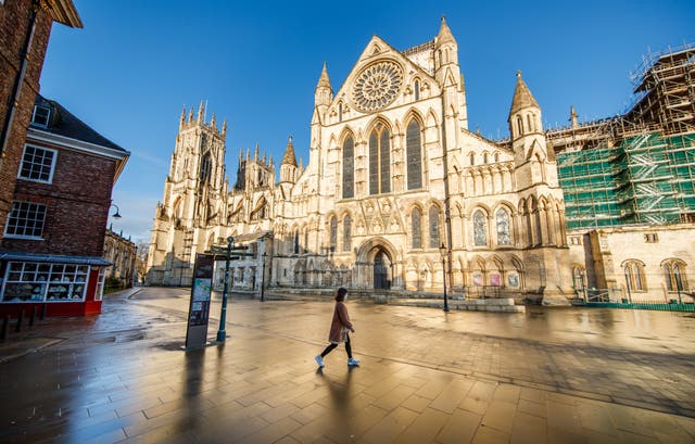 <p>A woman walks past York Minster in Yorkshire</p>
