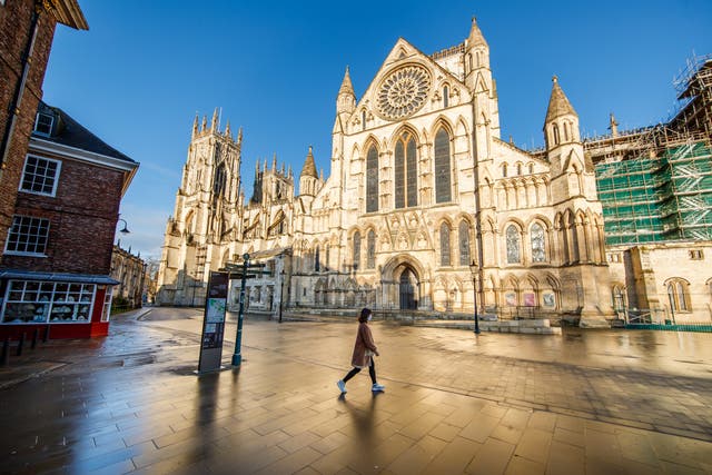 <p>A woman walks past York Minster in Yorkshire</p>