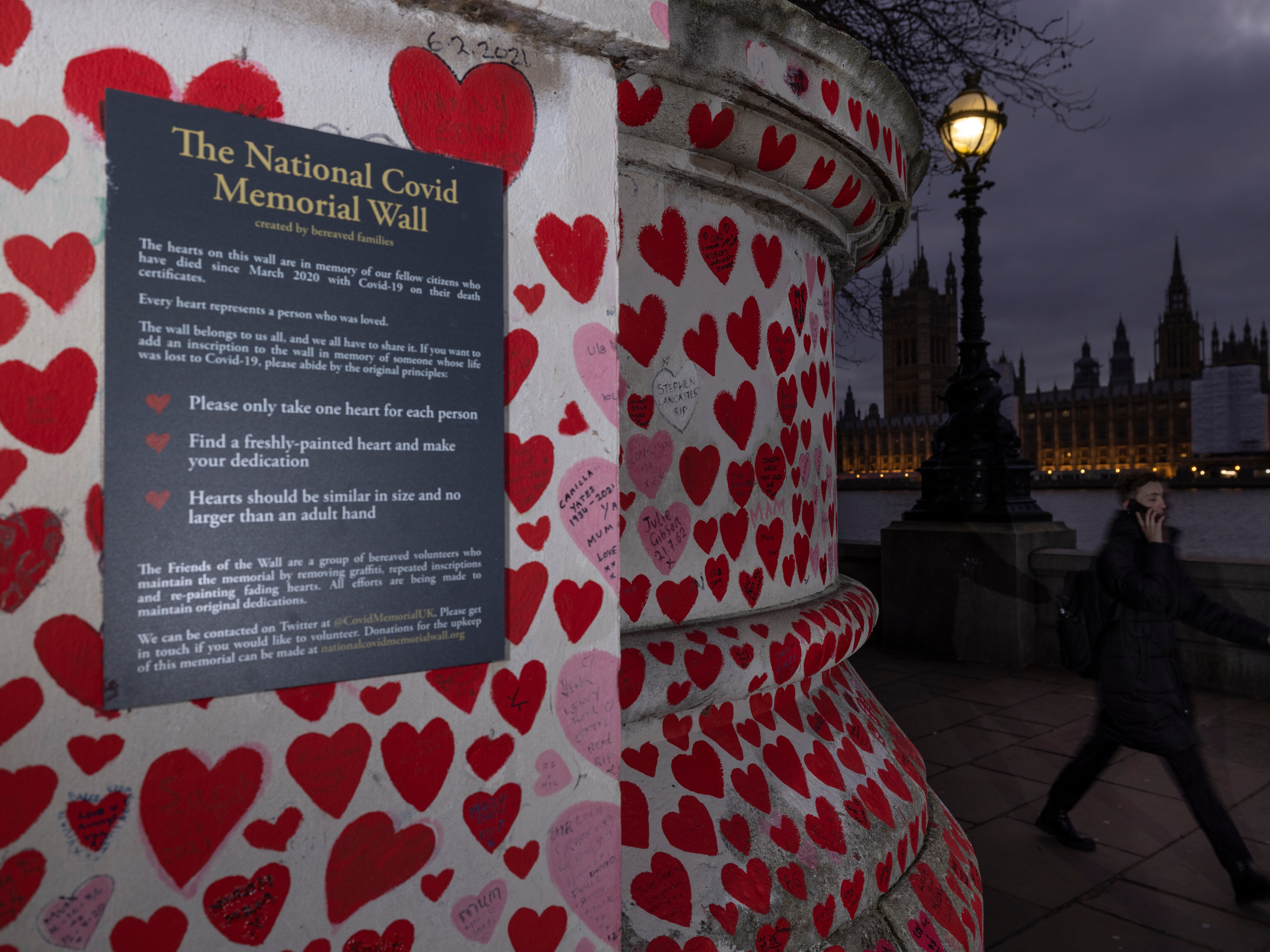 Members of the public walk past the National Covid Memorial wall, opposite parliament, as the government continues to face claims of unlawful parties during lockdown