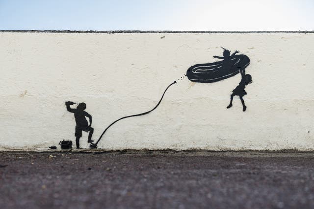 Banksy’s artwork on a promenade wall in Gorleston in Norfolk depicts children being propelled into the air on an overinflated dinghy (Banksy/PA)