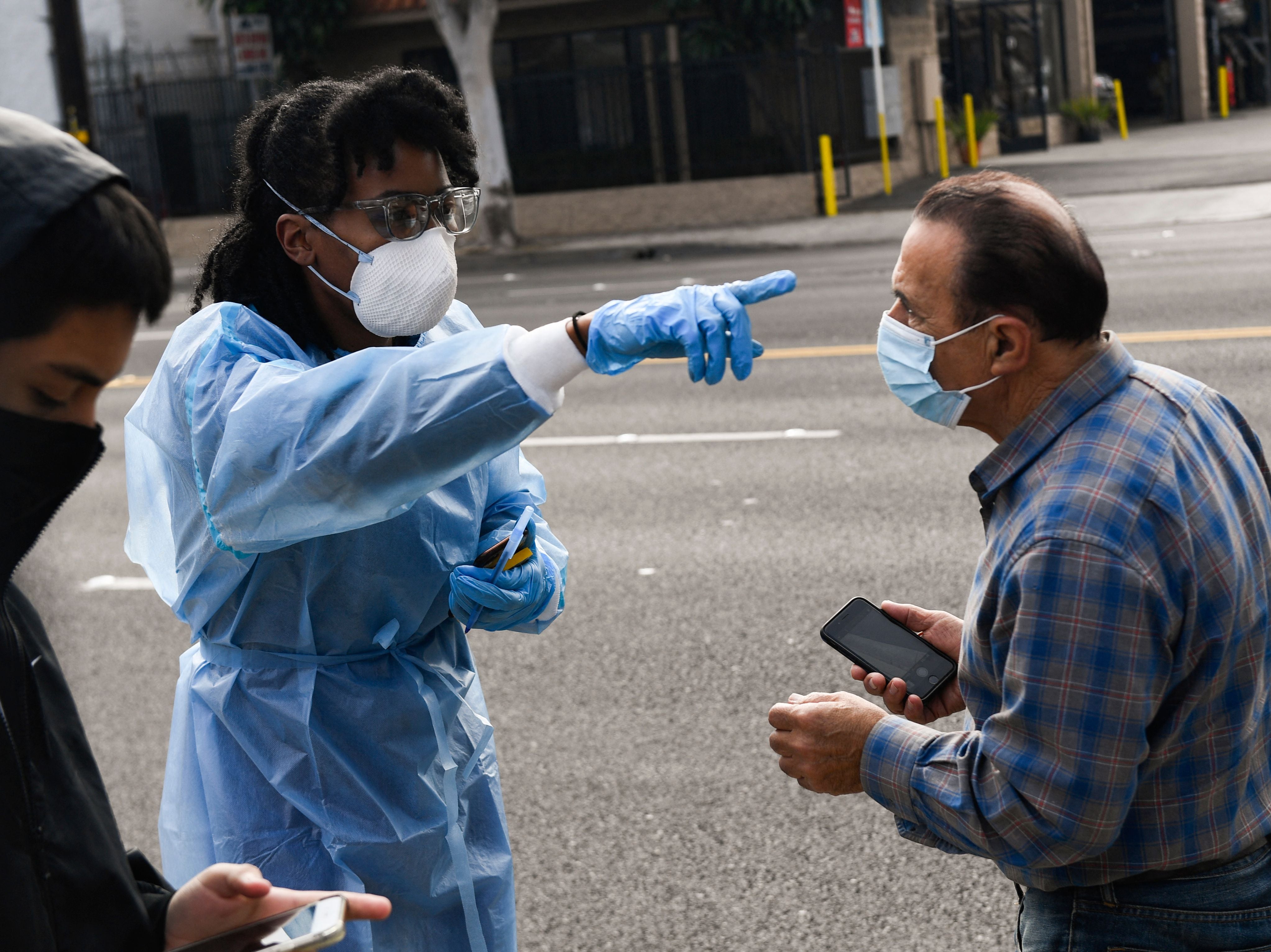 Un trabajador de la salud habla con las personas que esperan en la fila para recibir pruebas de antígeno rápido y PCR Covid-19 en un sitio de pruebas de Reliant Health Services en Hawthorne, California, el 18 de enero de 2022