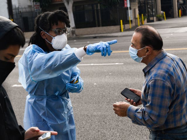 <p>A healthcare worker speaks to people waiting in line to receive testing for both rapid antigen and PCR Covid-19 tests at a Reliant Health Services testing site in Hawthorne, California on January 18, 2022</p>