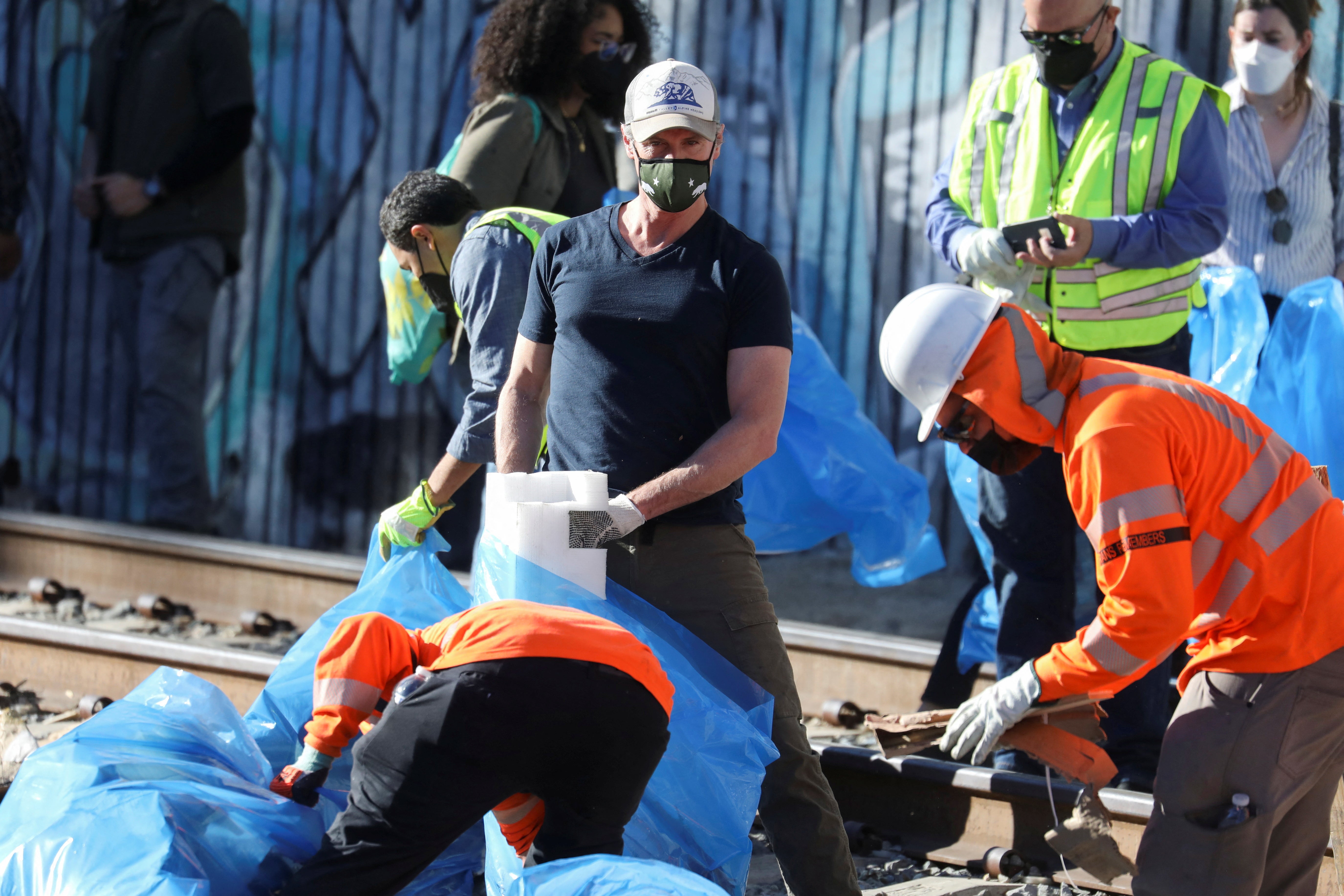 California Governor Gavin Newsom visits and helps clean the site where multiple train looting has occurred along the freight train tracks in Los Angeles, California U.S., January 20, 2022