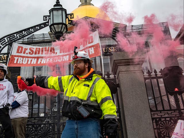 <p>A man releases smoke from a flare during a “truth, freedom rally” as hundreds of people protest against vaccines, vaccine mandates and vaccine passports at the State House in Boston, Massachusetts on January 5, 2022</p>