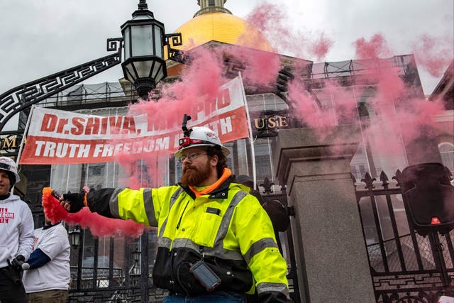 <p>A man releases smoke from a flare during a “truth, freedom rally” as hundreds of people protest against vaccines, vaccine mandates and vaccine passports at the State House in Boston, Massachusetts on January 5, 2022</p>
