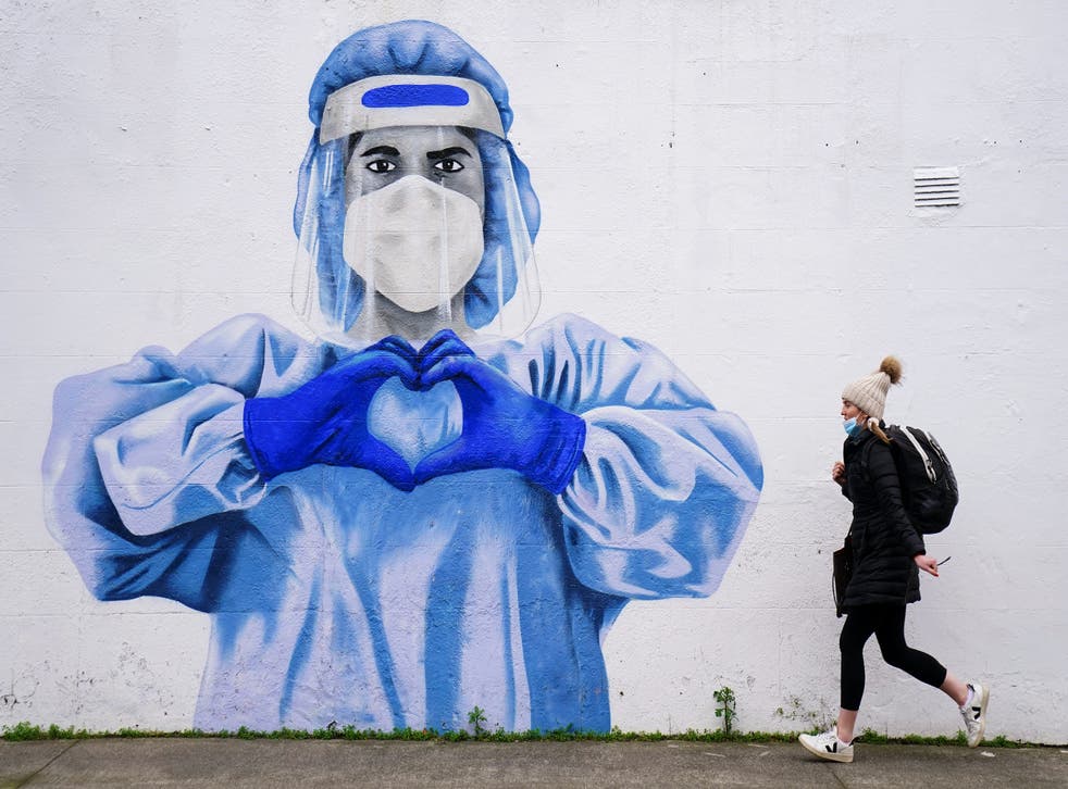 A woman passes a mural of a frontline worker in Dublin (PA)
