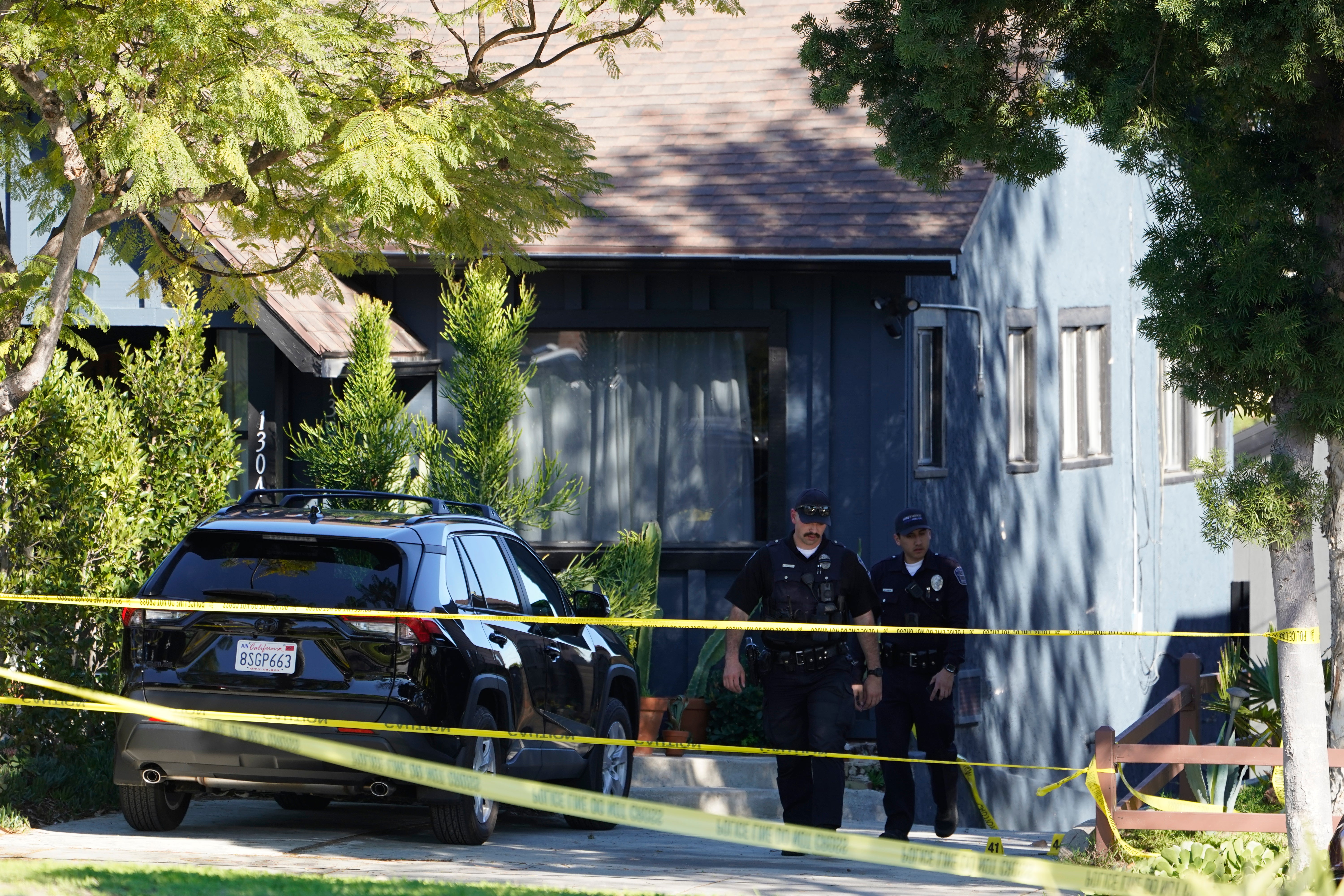 Police investigators leave a crime scene at a home in Inglewood, Calif., on Sunday
