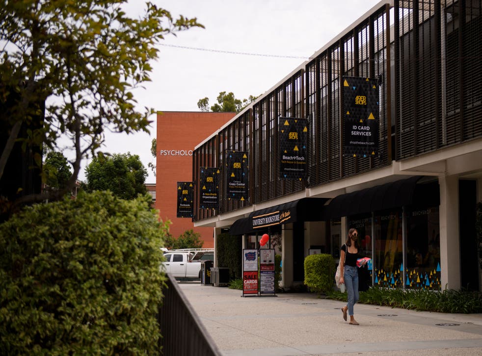 <p>File: A person wears a face mask as they walk past the University Bookstore at the California State University Long Beach (CSULB) campus on 11 August 2021 in Long Beach, California</p>