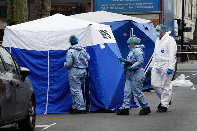 Metropolitan Police officers next to two forensic tents at the scene of the double death on Monday. (Aaron Chown/PA)