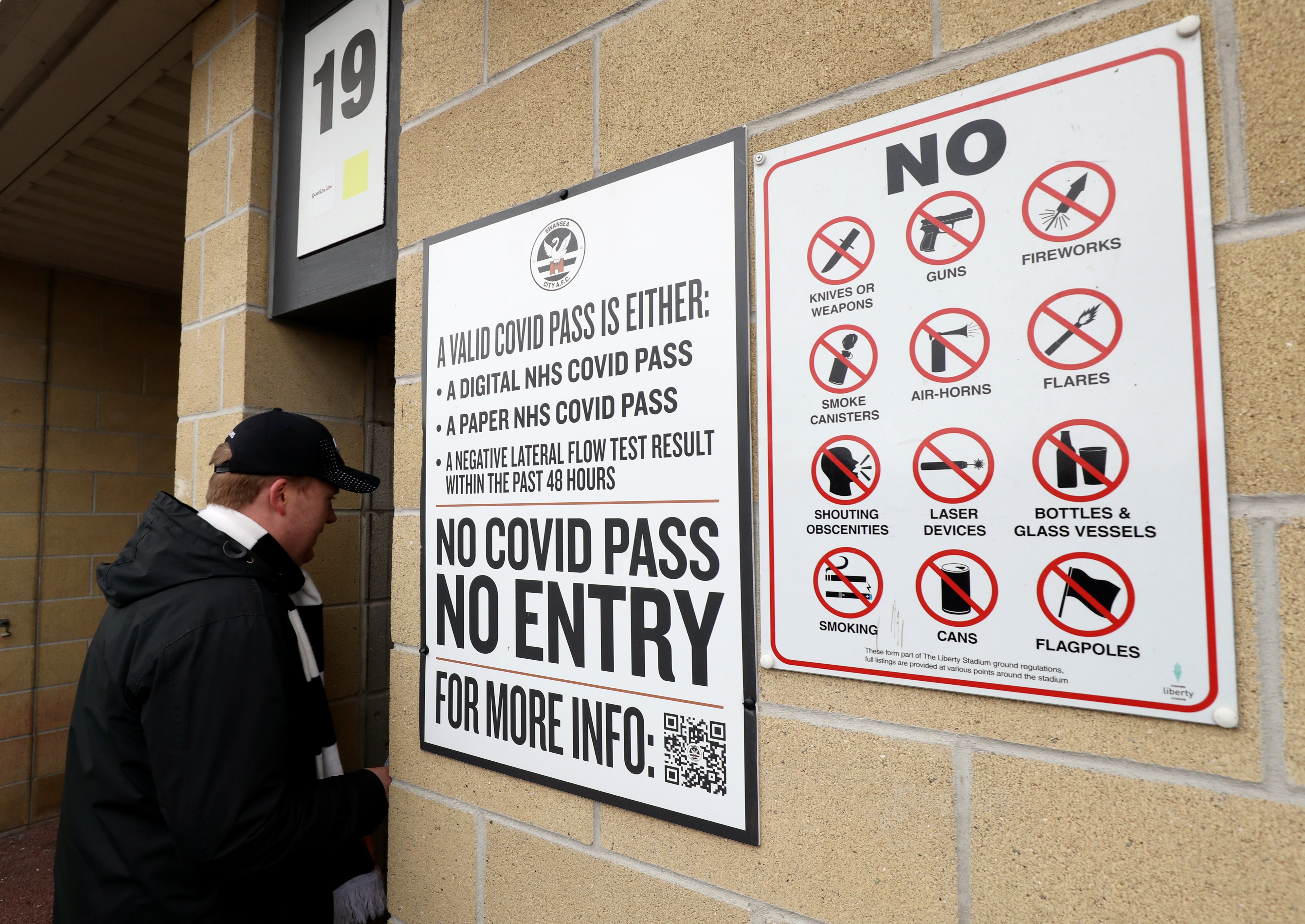A Swansea City fan enters the team’s stadium next to a notice about requirements for a Covid pass (Bradley Collyer/PA)