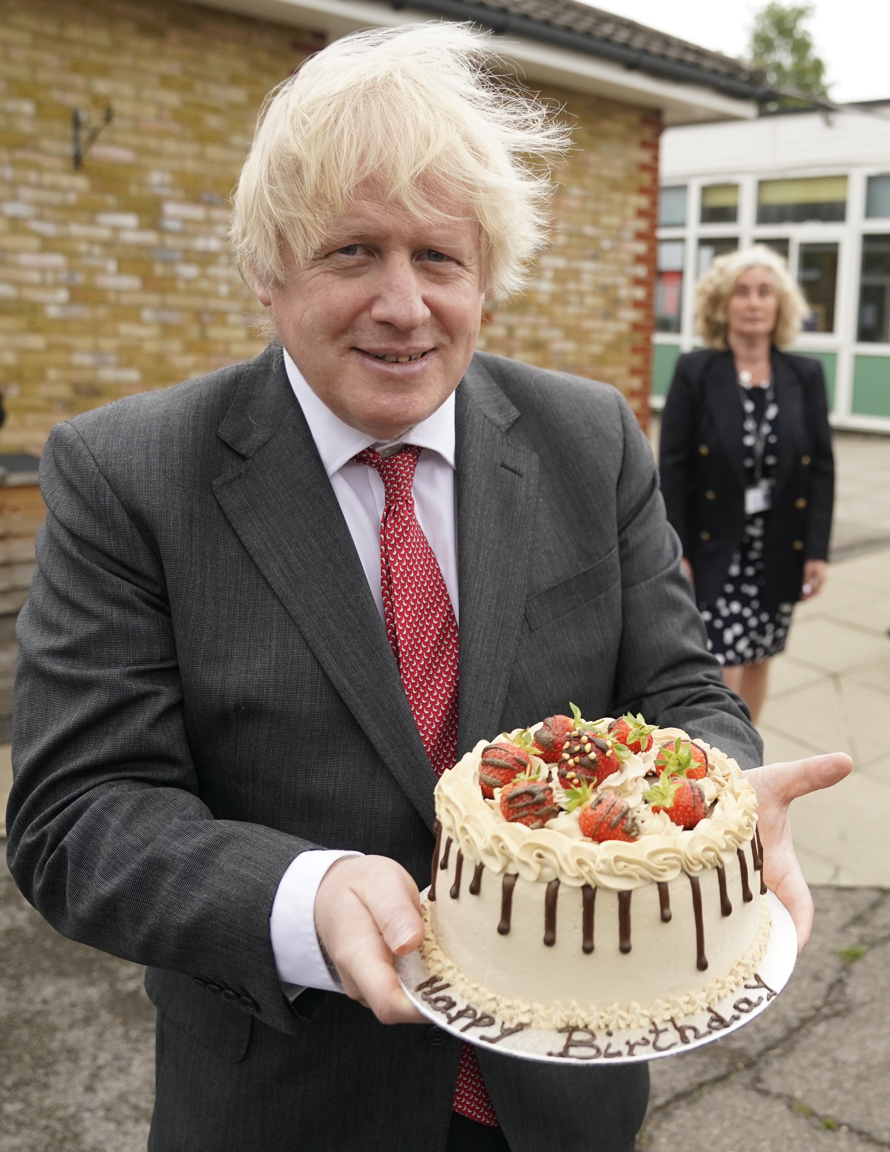 In this Downing Street handout photograph dated 19/6/2020 Boris Johnson holds up a birthday cake – baked for him by school staff – during a visit to Bovingdon Primary Academy (Andrew Parsons/Downing Street/PA)