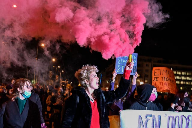 <p>A woman holds a flare as others hold placards, one of them reading ‘We are full of rage’, during a demonstration in support of victims of rape in Athens, earlier this month </p>