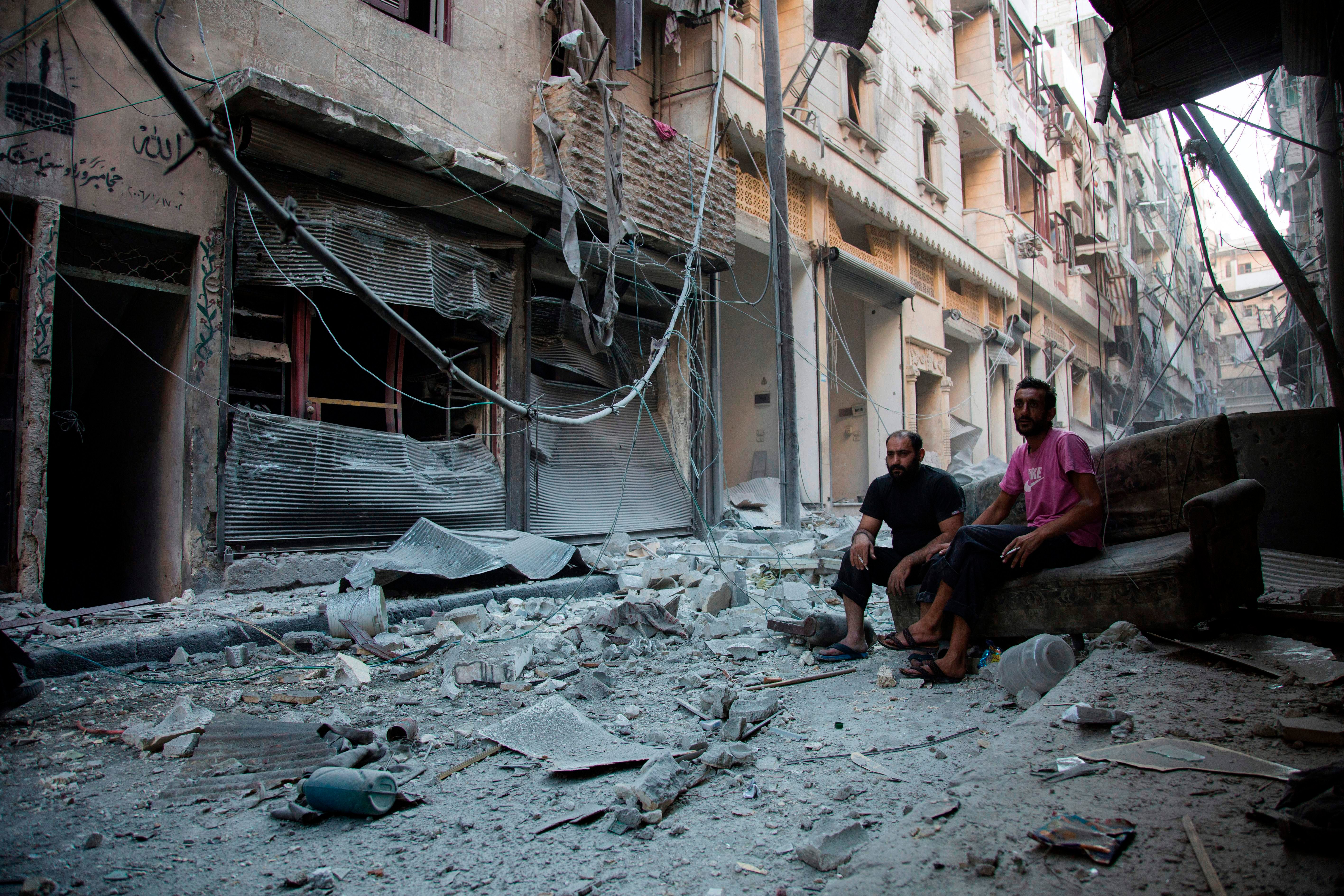 Syrians sit and look at the rubble following an air strike in Aleppo’s rebel-controlled neighbourhood of Karm al-Jabal in 2016