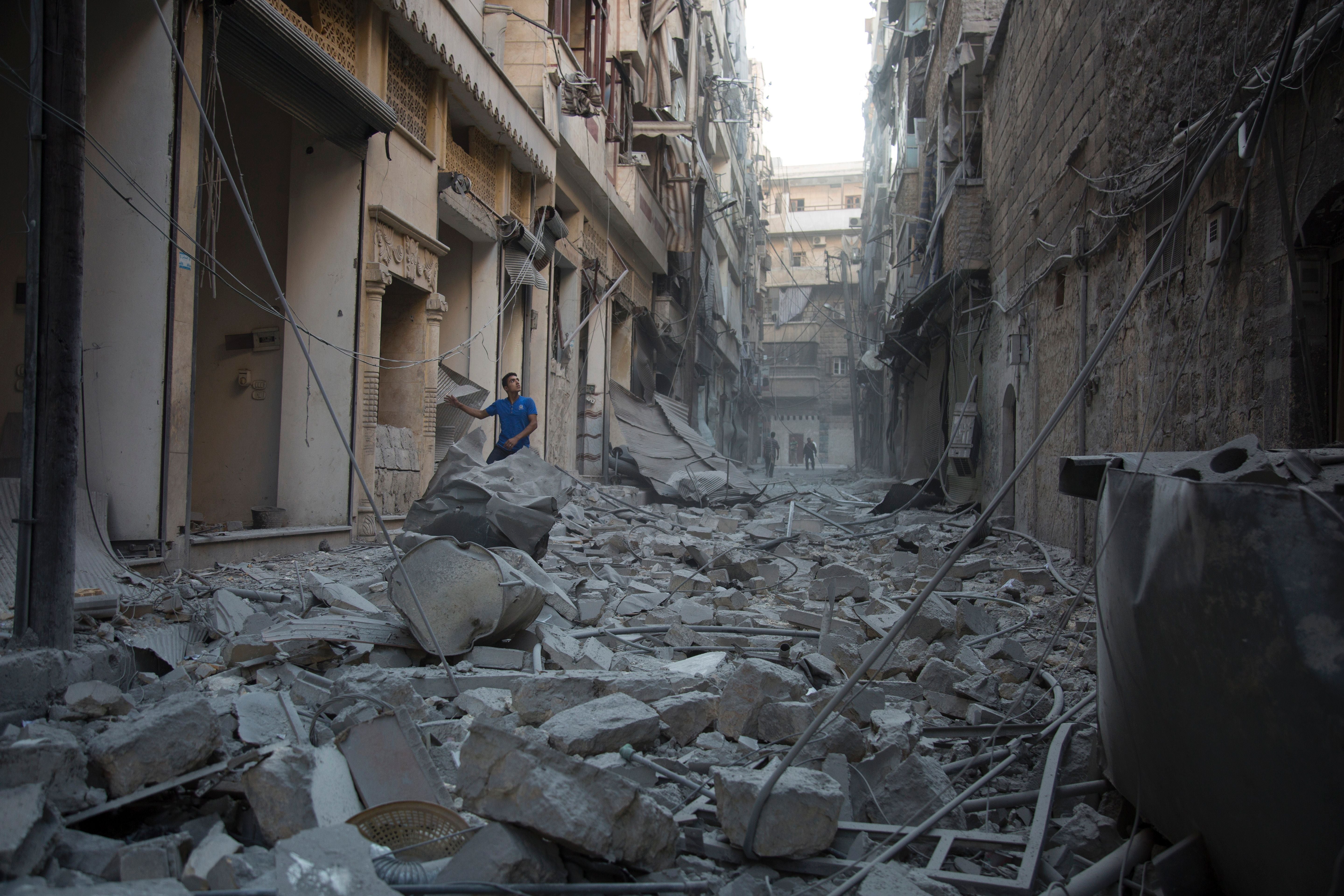 A Syrian man stands in the rubble of destroyed buildings following an air strike in Aleppo, 18 September, 2016